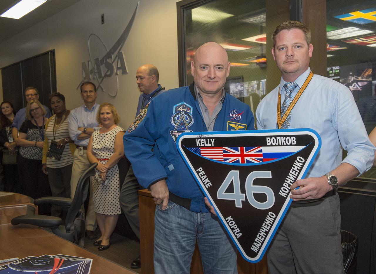 RETIRED NASA ASTRONAUT SCOTT KELLY, LEFT, AND PAYLOAD PLANNING MANAGER TONY PITTMAN PAUSE FOR A PHOTO BEFORE HANGING THE MISSION PATCH FOR EXPEDITION 46 ON THE WALL OF THE PAYLOAD OPERATIONS INTEGRATION CENTER