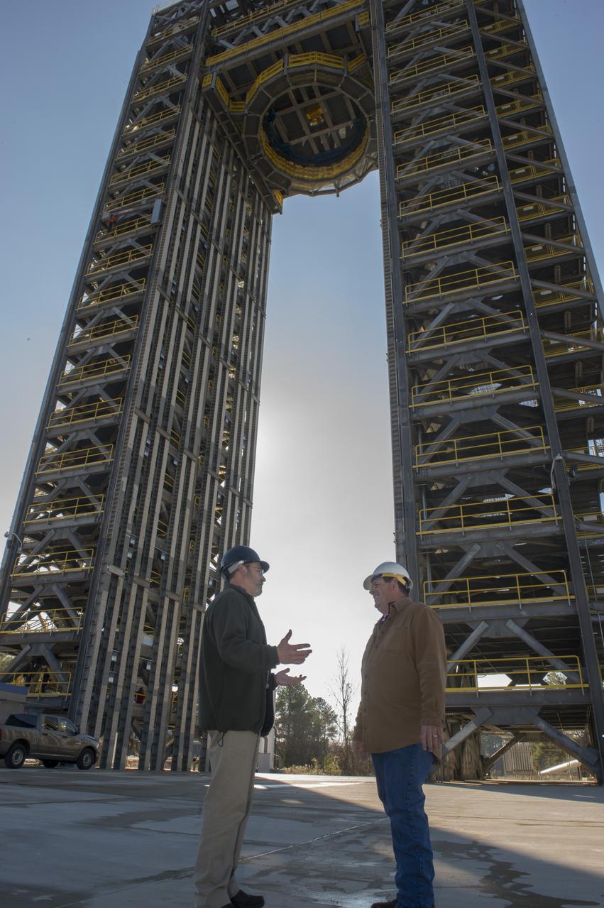 ROBERT BOBO, LEFT, AND MIKE NICHOLS TALK BENEATH THE 221-FOOT-TALL TEST STAND 4693, THE LARGEST OF TWO NEW SPACE LAUNCH SYSTEM TEST STANDS AT MSFC.  BOBO MANAGES SLS STRUCTURAL STRENGTH TESTING, AND NICHOLS IS LEAD TEST ENGINEER FOR THE SLS LIQUID HYDROGEN TANK.