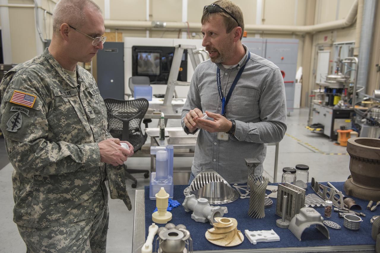 REDSTONE ARSENAL GARRISON COMMANDER COL. THOMAS "DOC" HOLLIDAY, LEFT, DISCUSSES THE PROCESSES AND HARDWARE USED IN NASA IN-SPACE MANUFACTURING TECHNIQUES WITH KEN COOPER, A STRUCTURAL MATERIALS ENGINEER AT NASA'S MARSHALL SPACE FLIGHT CENTER. COOPER, PART OF THE MARSHALL ENGINEERING DIRECTORATE'S ADVANCED MANUFACTURING AND DIGITAL SOLUTIONS TEAM, WAS AMONG NUMEROUS SUBJECT-MATTER EXPERTS WHO SHARED KEY MARSHALL CAPABILITIES DURING HOLLIDAY'S MARCH 3 MARSHALL TOUR. HOLLIDAY, A DECORATED OFFICER WHOSE MILITARY CAREER BEGAN IN 1992, GAINED FIRSTHAND INSIGHT INTO MARSHALL'S ADVANCED MANUFACTURING AND 3-D PRINTING TECHNIQUES; ROUND-THE-CLOCK INTERNATIONAL SPACE STATION SCIENCE AND COMMUNICATIONS SUPPORT BY THE PAYLOAD OPERATIONS INTEGRATION CENTER TEAM; AND THE LATEST UPGRADES TO MARSHALL TEST STANDS IN SUPPORT OF NEXT-GENERATION LAUNCH VEHICLE AND FLIGHT HARDWARE DEVELOPMENT. MARSHALL, A REDSTONE ARSENAL TENANT, ROUTINELY SHARES CUTTING-EDGE RESEARCH AND MANUFACTURING ADVANCES WITH ITS MILITARY AND FEDERAL AGENCY COUNTERPARTS, WORKING IN PARTNERSHIP TO ADVANCE NASA'S MISSION AND MAINTAIN THE NATION'S TECHNOLOGICAL LEADERSHIP.