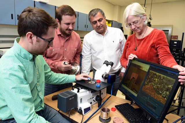 NASA image: Graduate students Chris Hill and Ryan Anderson examine a cross section of the prototype rocket engine igniter.