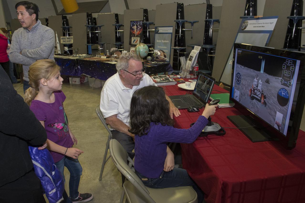 Marshall Space Flight Center retiree Ron Creel with young participant at LUROVA exhibit.  The event, hosted by the Planetary Missions Program at NASA's Marshall Space Flight Center, encourages observation and appreciation of the Moon and its connection to NASA planetary science and exploration, as well as our cultural and personal connections to it. Children attending the event had the opportunity to participate in planetary, science-based, hands-on activities