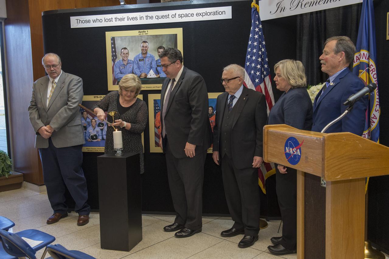 Jody Singer, Marshall deputy director, lights a candle in honor of colleagues who lost their lives in purist of space exploration during Marshall's Day of Remembrance ceremony. Looking on, from left, are Rick Burt, Marshall Safety and Mission Assurance Directorate director; Marshall Center Director Todd May; and former NASA astronauts retired Army Brig. Gen. Robert Stewart; former Marshall Deputy Director Jan Davis; and Robert "Hoot" Gibson. 