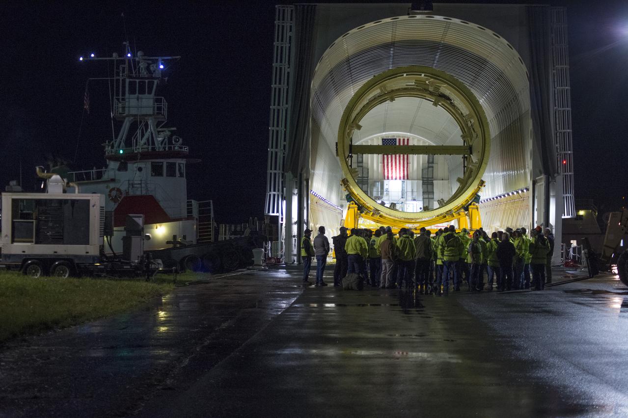 The SLS Stages Intertank Structural Test Assembly (STA) is rolling off the NASA Pegasus Barge at the MSFC Dock enroute to the MSFC 4619 Load Test Annex test facility for qualification testing. Members of MSFC Logistics Office and Move Team members gather for last minute instructions and safety briefing before off-loading STA hardware.