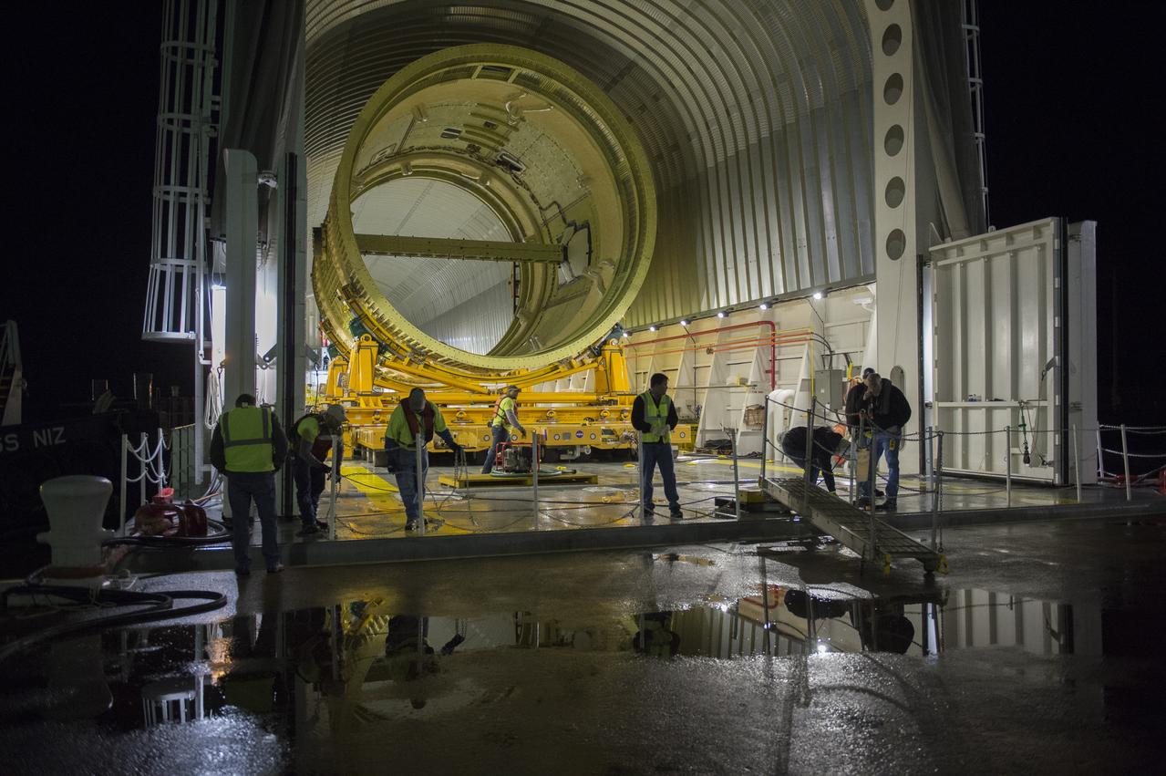 The SLS Stages Intertank Structural Test Assembly (STA) is rolling off the NASA Pegasus Barge at the MSFC Dock enroute to the MSFC 4619 Load Test Annex test facility for qualification testing