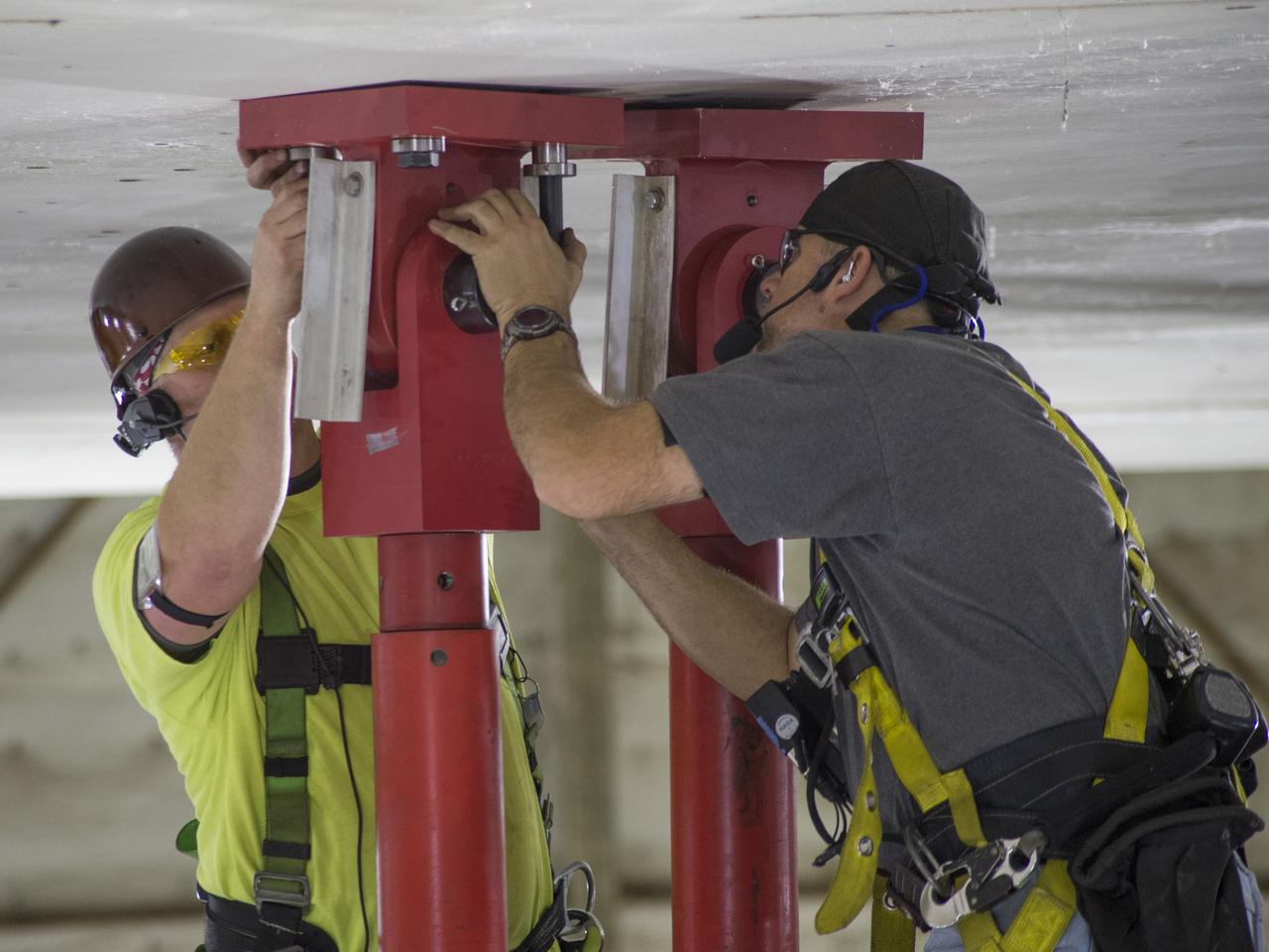 SLS Intertank Test Article, ITA, is attached to crosshead of load test Annex, Bldg. 4619, and removed from bed of KMAG transporter.  Rob Ziegler, L, and Roger Myrick, R, of Aerie Aerospace attach load lines to Aft Load Ring of Intertank Test Articlle
