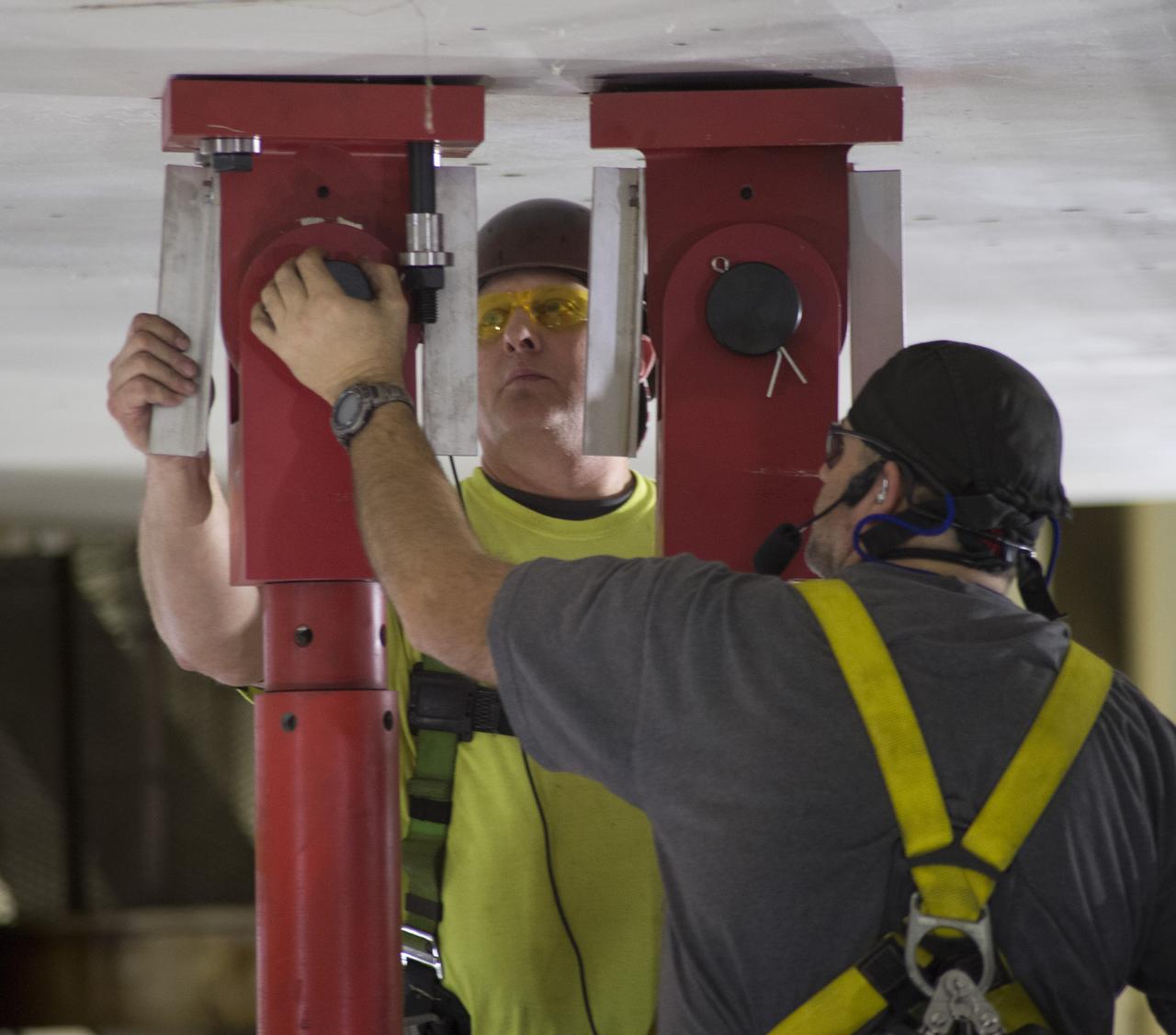 SLS Intertank Test Article, ITA, is attached to crosshead of load test Annex, Bldg. 4619, and removed from bed of KMAG transporter. Rob Ziegler, (L), and Roger Myrick (R), of Aerie Aerospace attach load lines to Aft Load Ring of Intertank Test Article. 