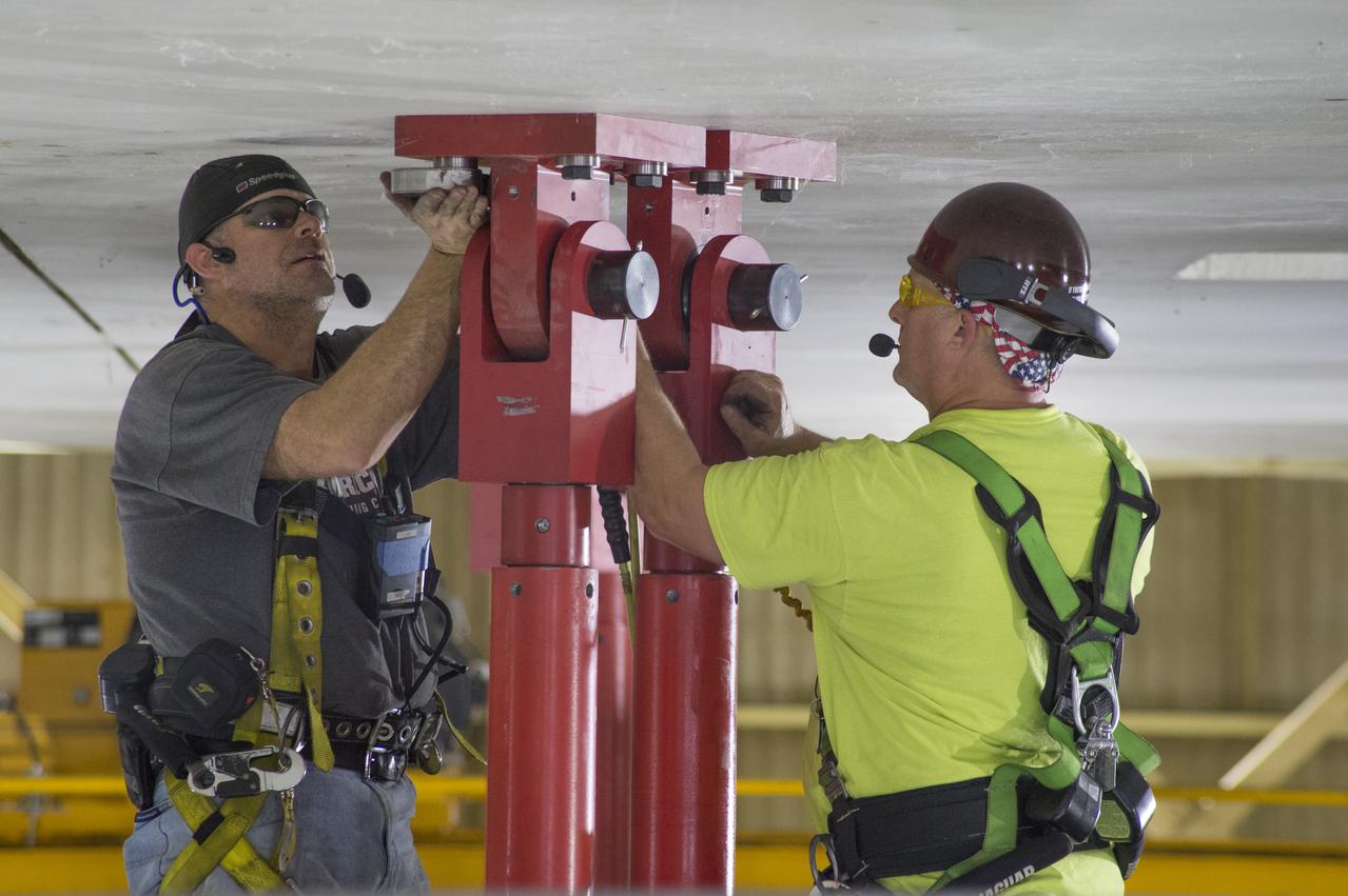 SLS Intertank Test Article, ITA, is attached to crosshead of load test Annex, Bldg. 4619, and removed from bed of KMAG transporter.  Rob Ziegler, (L), and Roger Myrick (R), of Aerie Aerospace attach load lines to Aft Load Ring of Intertank Test Article.