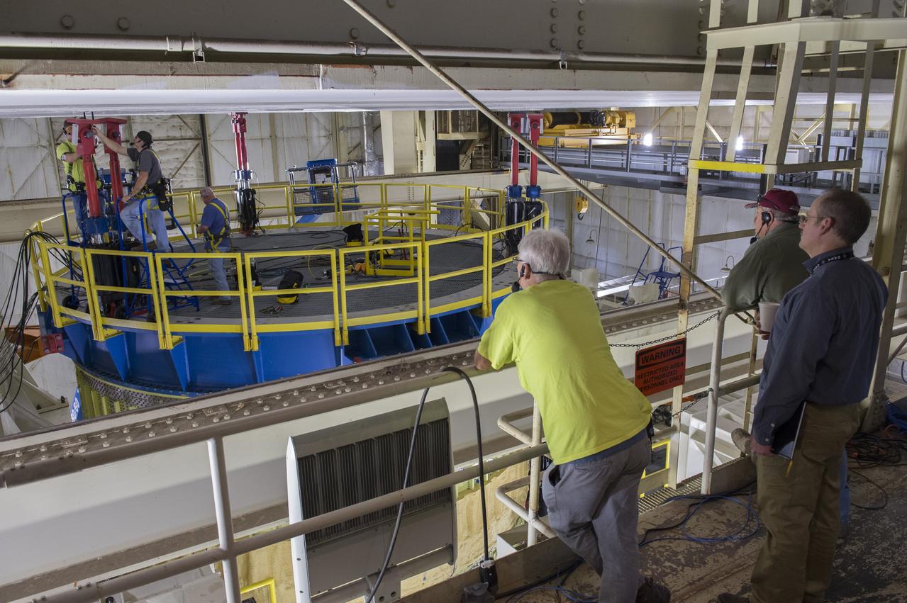 Robert Bobo, standing extreme right, and technicians view as SLS Intertank Test Article, ITA, is attached to crosshead of load test Annex, Bldg. 4619
