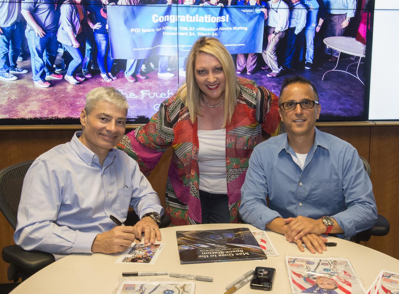 NASA astronauts Joe Acaba and Mark Vande Hei Acaba visited Marshall April 11 for their honorary Expedition 54 plaque hanging ceremony and to provide valuable feedback of their on-orbit science investigations with the Payload Operations and Integration Center team. Astronauts Mark Vande Hei (L) and Astronaut Joe Acaba sign autographs for Lori Meggs.
