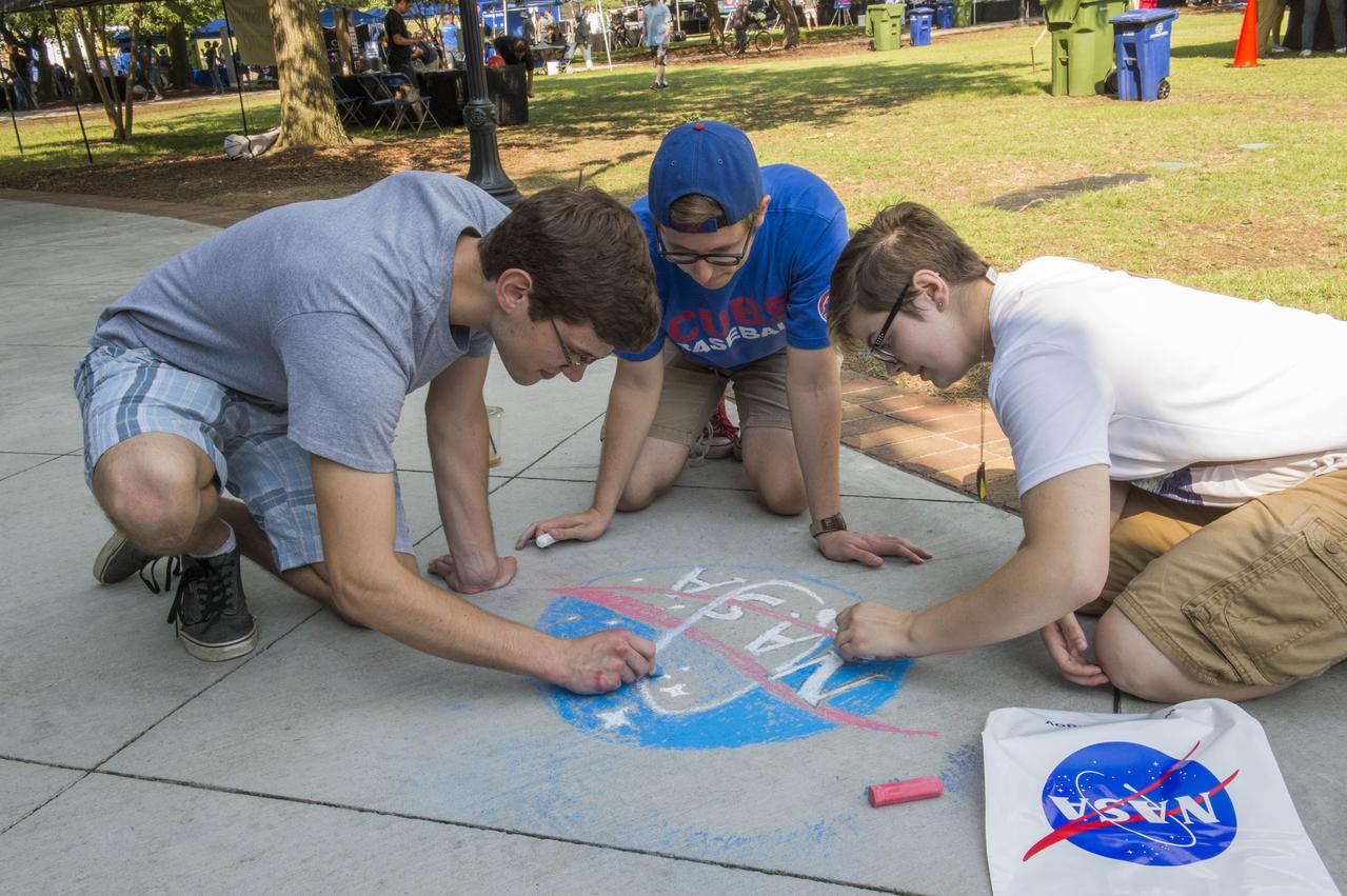 NASA in the Park on June 16 in Huntsville featured more than 60 exhibits and demonstrations by NASA experts, as well as performances by Marshall musicians, educational opportunities, games and hands-on activities for all ages. MSFC Summer Interns Eben Lenfest, Nick Bonini, and April Benedict display their artistic talents on Big Spring Park sidewalk during NASA in the Park festivities.  