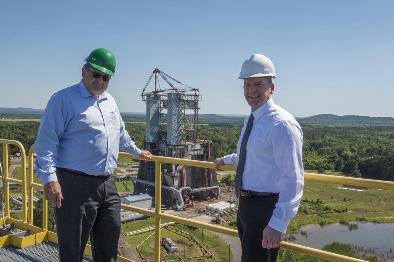 MSFC Director Todd May and FBI Associate Deputy Director Paul Abbate pose atop SLS Test Stand 4693 with historic TTB test stand in background