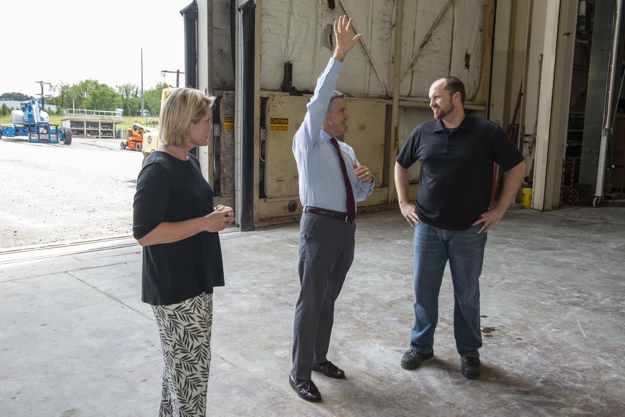 Kennedy Space Center Director Robert Cabana, center, receives an update on SLS hardware from Heather Haney, left, an engineer in the Space Launch System stages office, and Mark White, lead test engineer for the SLS core stage engine section, on July 16 in Marshall's Building 4619. Cabana, Haney and White are standing in front of a structural test version of the Intertank, the 212-foot-tall backbone of the SLS rocket. The structural test article is undergoing critical testing as engineers push, pull and bend the hardware with millions of pounds of force to ensure it can withstand the forces of launch and ascent. 