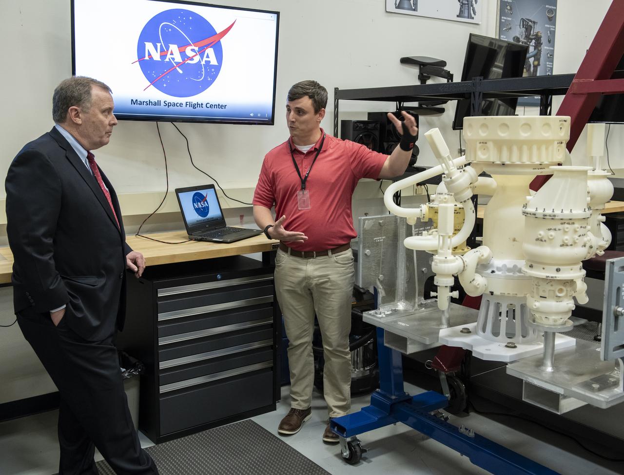 NASA Deputy Administrator Jim Morhard, left, visits the Combustion Lab at Marshall Space Flight Center on March 25, where Michael Allison shares the advancements being made in additive manufacturing of rocket engine parts at Marshall. Allison leads the assembly and integration lead for the MC2 engine model, shown here, which is an additively manufactured liquid engine designed and developed at Marshall. During his tour of the center, Morhard also saw the work being done by Marshall to advance deep space exploration at the Liquid Hydrogen Test Stand, Deep Space Habitat, Payload Operations Integration Center and the Systems Integration Lab.
