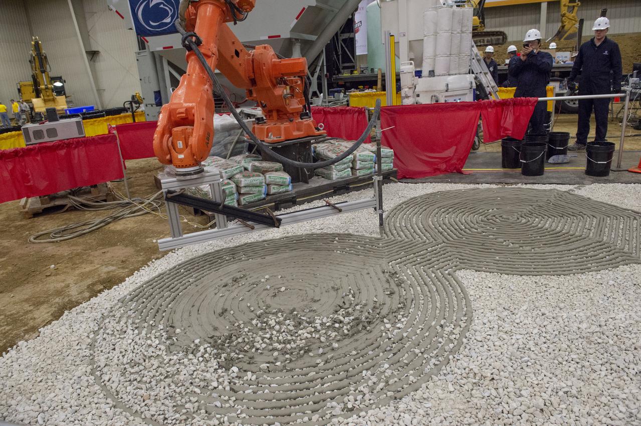 AI. SpaceFactory of New York and Pennsylvania State University of College Park print subscale habitat structures at NASA's 3D-Printed Habitat Challenge, held at the Caterpillar Edwards Demonstration & Learning Center in Edwards, Illinois, May 1-4, 2019. The habitat print is the final level of the multi-phase competition, which began in in 2015. The challenge is managed by NASA's Centennial Challenges program, and partner Bradley University of Peoria, Illinois.  Initial footprint of 3D material laydown for Penn State habitat.