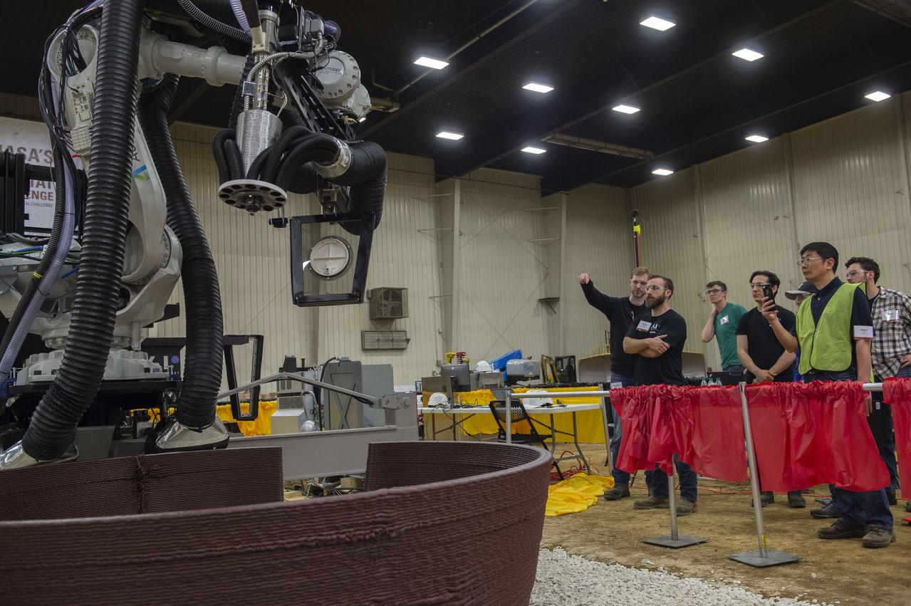 AI. SpaceFactory of New York and Pennsylvania State University of College Park print subscale habitat structures at NASA's 3D-Printed Habitat Challenge, held at the Caterpillar Edwards Demonstration & Learning Center in Edwards, Illinois, May 1-4, 2019. The habitat print is the final level of the multi-phase competition, which began in in 2015. The challenge is managed by NASA's Centennial Challenges program, and partner Bradley University of Peoria, Illinois.  First window placement in AI Spacefactory habitat.