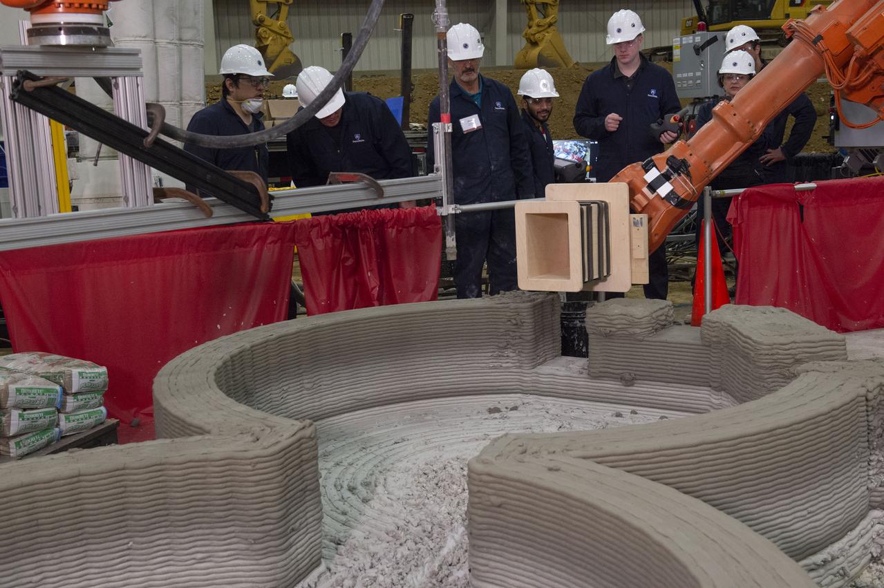 AI. SpaceFactory of New York and Pennsylvania State University of College Park print subscale habitat structures at NASA's 3D-Printed Habitat Challenge, held at the Caterpillar Edwards Demonstration & Learning Center in Edwards, Illinois, May 1-4, 2019. The habitat print is the final level of the multi-phase competition, which began in in 2015. The challenge is managed by NASA's Centennial Challenges program, and partner Bradley University of Peoria, Illinois.  Insertion of window element in Penn State Habitat.