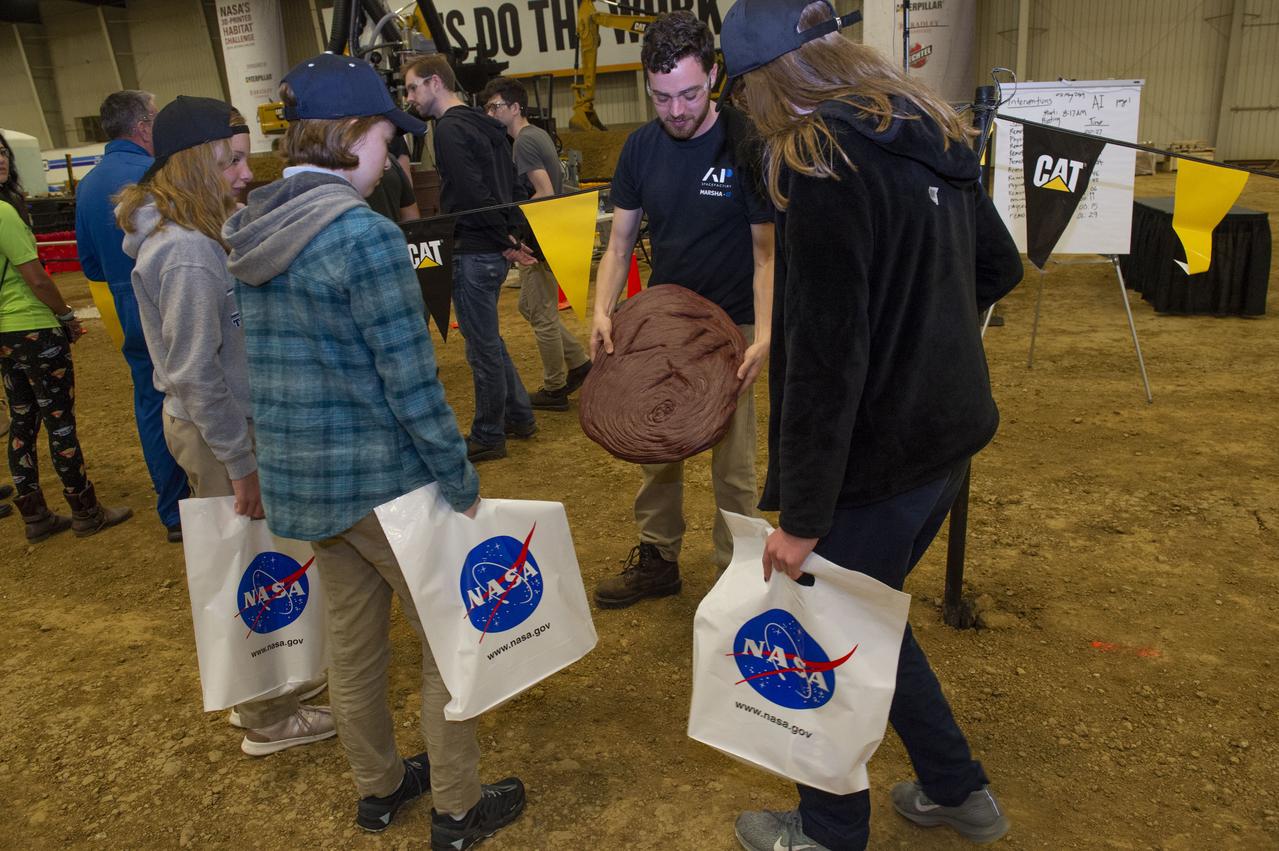 AI. SpaceFactory of New York and Pennsylvania State University of College Park print subscale habitat structures at NASA's 3D-Printed Habitat Challenge, held at the Caterpillar Edwards Demonstration & Learning Center in Edwards, Illinois, May 1-4, 2019. The habitat print is the final level of the multi-phase competition, which began in in 2015. The challenge is managed by NASA's Centennial Challenges program, and partner Bradley University of Peoria, Illinois.  AI team member shows early unsuccessful attempt at printing to students viewing the competition.