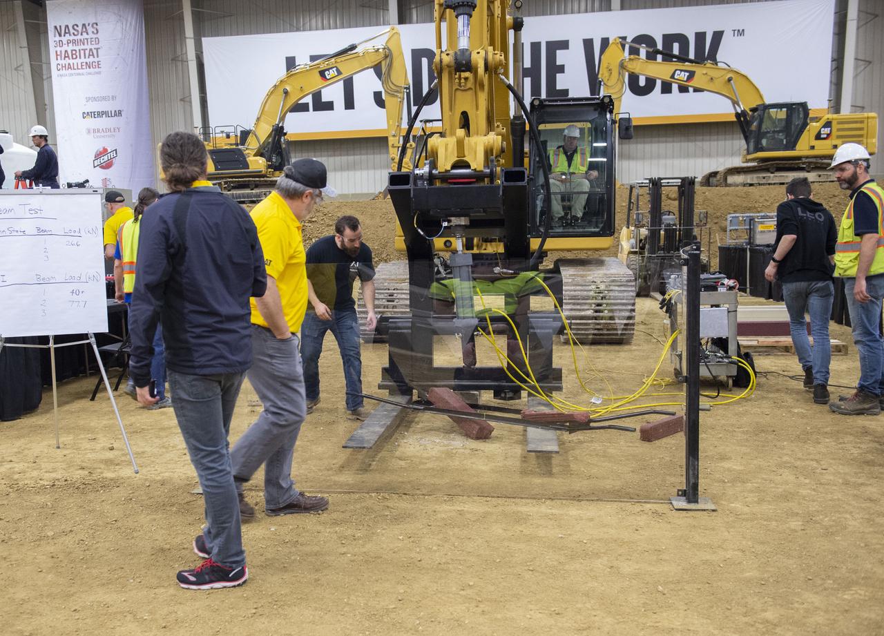 AI. SpaceFactory of New York and Pennsylvania State University of College Park print subscale habitat structures at NASA's 3D-Printed Habitat Challenge, held at the Caterpillar Edwards Demonstration & Learning Center in Edwards, Illinois, May 1-4, 2019. The habitat print is the final level of the multi-phase competition, which began in in 2015. The challenge is managed by NASA's Centennial Challenges program, and partner Bradley University of Peoria, Illinois.  Strength testing of composite material used for habitat construction by AI Spacefactory. 