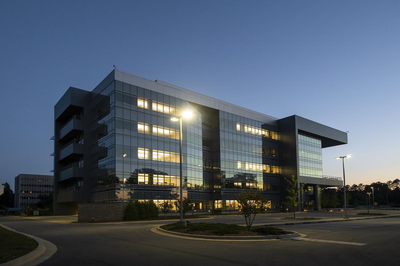 At dusk, the northern side of Building 4221 on Marshall Space Flight Center’s campus is silhouetted against blue skies.