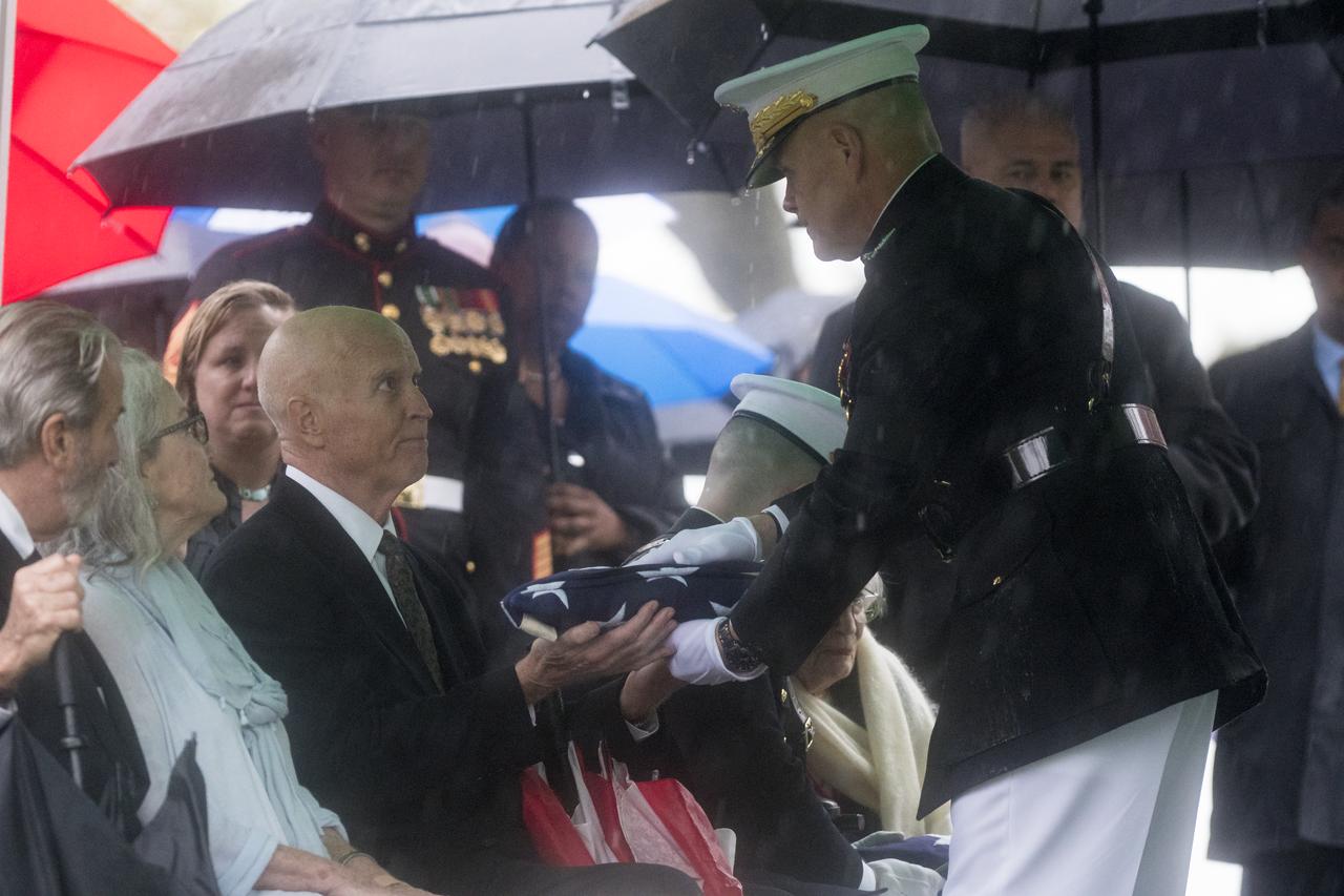 David Glenn, son of former astronaut and U.S. Senator John Glenn receives the folded American flag from the Commandant of the U.S. Marine Corps, General Robert B. Neller, during a graveside interment ceremony at Arlington National Cemetery on Thursday, April 6, 2017 in Virginia. He was the first American to orbit Earth on Feb. 20, 1962, in a five-hour flight aboard the Friendship 7 spacecraft. In 1998, Glenn broke another record by returning to space at the age of 77 on the Space Shuttle Discovery. Photo Credit: (NASA/Aubrey Gemignani)