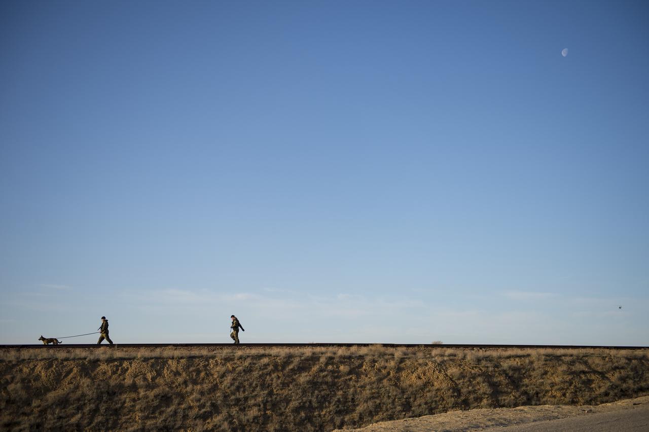 The moon is seen as Russian security officers inspect the tracks before the Soyuz rocket is rolled out to the launch pad on Monday, April 17, 2017 at the Baikonur Cosmodrome in Kazakhstan. The Soyuz MS-04 spacecraft, scheduled to launch April 20 Baikonur time, will carry Expedition 51 Soyuz Commander Fyodor Yurchikhin of Roscosmos and Flight Engineer Jack Fischer of NASA into orbit to begin their four and a half month mission on the International Space Station. Photo Credit: (NASA/Aubrey Gemignani)