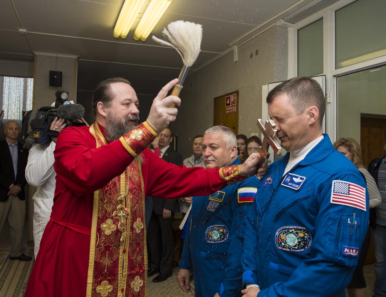 Expedition 51 Flight Engineer Jack Fischer of NASA, right, receives the traditional blessing from a Russian Orthodox priest at the Cosmonaut Hotel prior to his launch on the Soyuz rocket to the International Space Station (ISS), Thursday, April 20, 2017, in Baikonur, Kazakhstan. He and fellow crew mate, Soyuz Commander Fyodor Yurchikhin of Roscosmos, left, will spend the next four and a half months living and working aboard the ISS. Photo Credit: (NASA/Aubrey Gemignani)