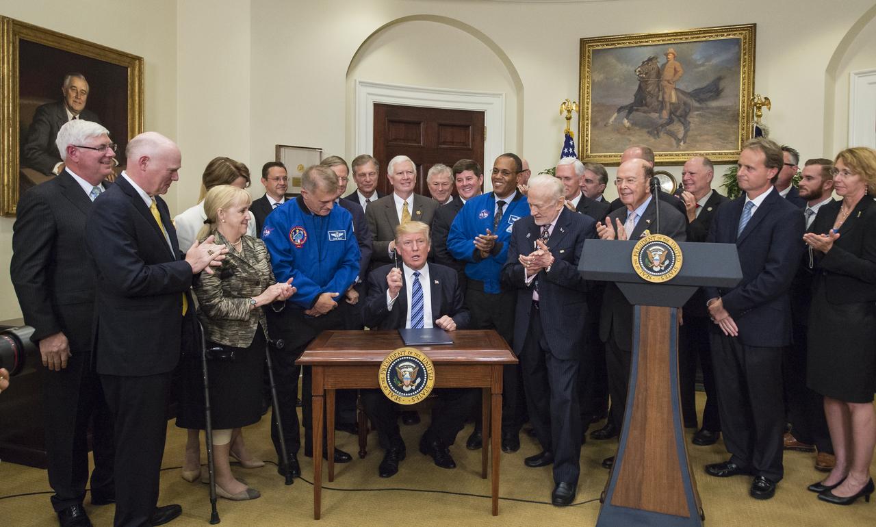 President Donald Trump, center, asks who should receive the pen after signing an Executive Order to reestablish the National Space Council, alongside members of the Congress, National Aeronautics and Space Administration, and Commercial Space Companies in the Roosevelt room of the White House in Washington, Friday, June 30, 2017. Retired astronaut Buzz Aldrin was given the pen. Also pictured are, Vice President Mike Pence, Rep. Bill Posey, R-Florida, Rep. Lamar Smith, R-Texas, Rep. John Culberson, R-Texas, Rep. Steven Palazzo, R-Miss., Rep. Brian Babin, R-Texas, Rep. Mo Brooks, R-Alabama, Rep. Dana Rohrbacher, R-California, Former Rep. Bob Walker, R-Pennsylvania, Sandy Magnus, executive director, American Institute of Aeronautics and Astronautics, David Melcher, executive director, Aerospace Industries Association, Tory Bruno, CEO, United Launch Alliance, Michal Riley, CEO, AMRO Fabricating Corporation, John Couch, president, Futuramic, Mike Cain, owner, Cain Tubular Products, Mary Lynne Dittmar, executive director, Coalition for Deep Space Exploration, Dennis Muilenburg, CEO Boeing Company, Marilyn Hewson, CEO, Lockheed Martin, Wes Bush, CEO, Northrop Grumman, NASA Astronaut Alvin Drew, retired NASA astronaut David Wolf, Apollo 13 flight director, Gene Kranz, Secretary of Commerce Wilbur Ross, Under Secretary of the Air Force Lisa Disbrow, and Acting Deputy Director of National Intelligence, Dawn Eilengerger. Photo Credit: (NASA/Aubrey Gemignani)