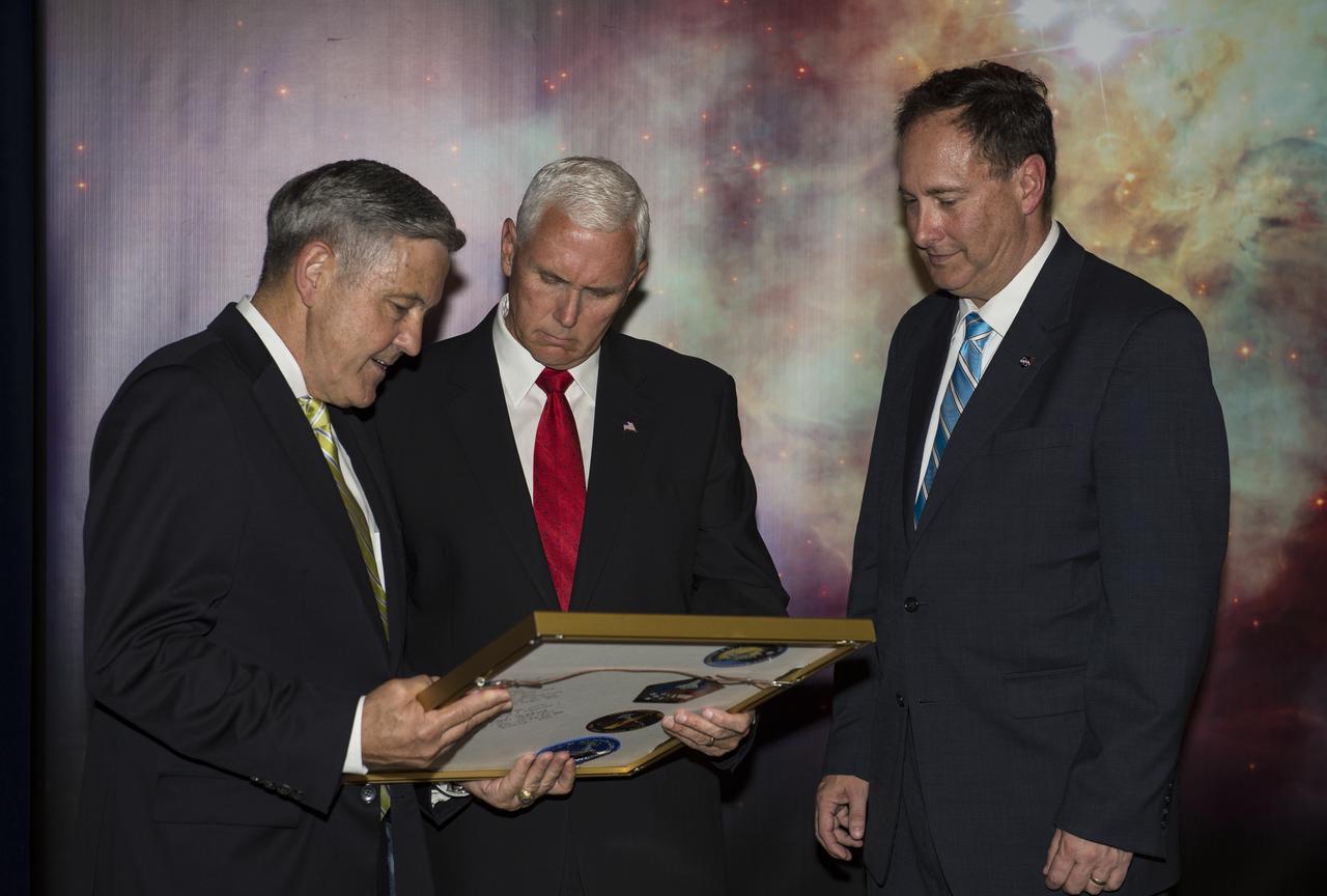 Vice President Mike Pence receives a commemorative montage including an Indiana flag, representing the Vice President's hometown, that was flown in space, from NASA's Kennedy Space Center (KSC) Director, Robert Cabana, left, and Acting NASA Administrator, Robert Lightfoot, right, Thursday, July 6, 2017, in the green room at NASA’s Kennedy Space Center (KSC) in Cape Canaveral, Florida. Vice President Mike Pence is scheduled to speak at the event to highlight innovations made in America and tour some of the public/private partnership work that is helping to transform the center into a multi-user spaceport. Photo Credit: (NASA/Aubrey Gemignani)