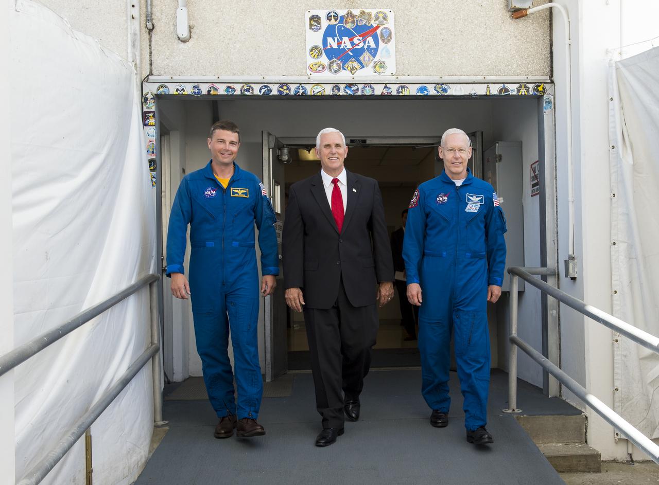 Vice President Mike Pence, center, and NASA astronaut Reid Wiseman, left, and NASA astronaut Pat Forrester, right, walk out of the historic crew doors at Kennedy Space Center's (KSC) Operations and Checkout Building on Thursday, July 6, 2017, in Cape Canaveral, Florida. These are the same doors that Apollo and space shuttle astronauts walked through on their way to the launch pad. Photo Credit: (NASA/Aubrey Gemignani)