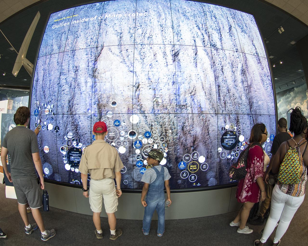 Visitors explore an interactive map of the surface of Mars at the Smithsonian Institution’s National Air and Space Museum Mars Day, an annual event celebrating the Red Planet with exhibits, speakers, and educational activities, Friday, July 21, 2017 in Washington. Photo Credit: (NASA/Aubrey Gemignani)