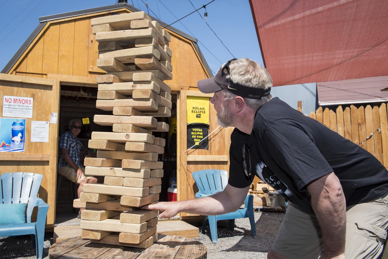 Eirik Olsen, of Seattle, Washington, plays giant Jenga while waiting to watch the total solar eclipse in Madras, Oregon on Saturday, August 19, 2017. The eclipse will be sweeping across a narrow portion of the contiguous United States from Lincoln Beach, Oregon to Charleston, South Carolina on August 21. A partial solar eclipse will be visible across the entire North American continent along with parts of South America, Africa, and Europe.  Photo Credit: (NASA/Aubrey Gemignani)