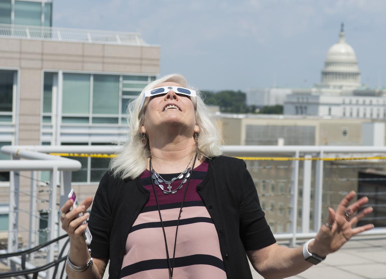 NASA employees and contractors use protective glasses to view a partial solar eclipse from NASA Headquarters Monday, Aug. 21, 2017 in Washington. A total solar eclipse swept across a narrow portion of the contiguous United States from Lincoln Beach, Oregon to Charleston, South Carolina. A partial solar eclipse was visible across the entire North American continent along with parts of South America, Africa, and Europe.  Photo Credit: (NASA/Gwen Pitman)