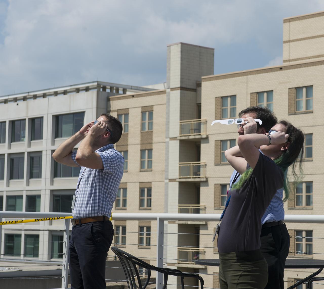 NASA employees and contractors use protective glasses to view a partial solar eclipse from NASA Headquarters Tuesday, Aug. 22, 2017 in Washington. A total solar eclipse swept across a narrow portion of the contiguous United States from Lincoln Beach, Oregon to Charleston, South Carolina. A partial solar eclipse was visible across the entire North American continent along with parts of South America, Africa, and Europe.  Photo Credit: (NASA/Gwen Pitman)