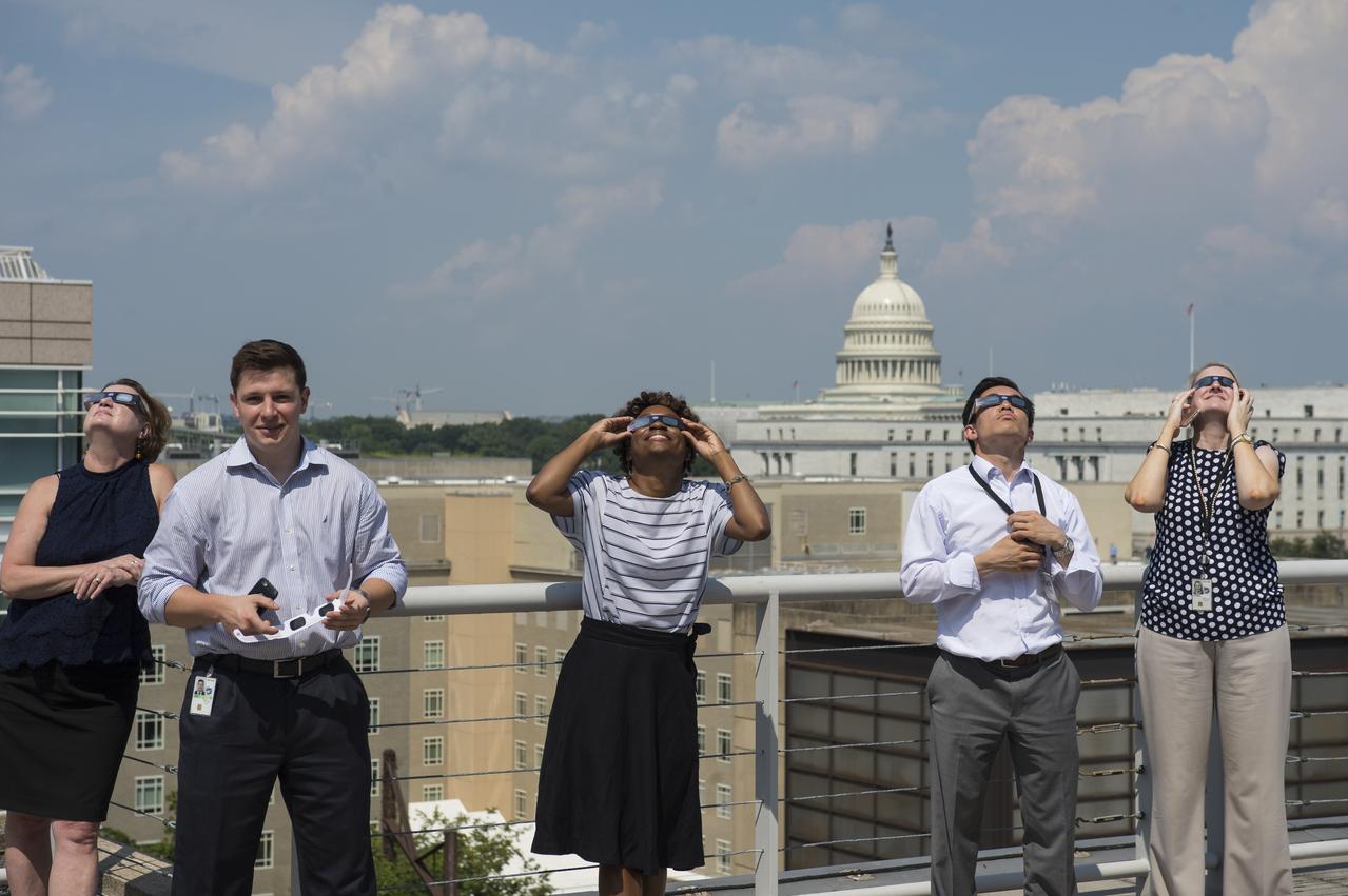 NASA employees and contractors use protective glasses to view a partial solar eclipse from NASA Headquarters Tuesday, Aug. 22, 2017 in Washington. A total solar eclipse swept across a narrow portion of the contiguous United States from Lincoln Beach, Oregon to Charleston, South Carolina. A partial solar eclipse was visible across the entire North American continent along with parts of South America, Africa, and Europe.  Photo Credit: (NASA/Gwen Pitman)