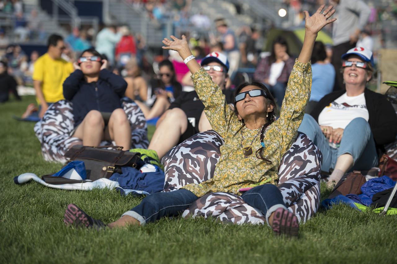 People are seen as they watch a total solar eclipse through protective glasses in Madras, Oregon on Monday, Aug. 21, 2017. A total solar eclipse swept across a narrow portion of the contiguous United States from Lincoln Beach, Oregon to Charleston, South Carolina. A partial solar eclipse was visible across the entire North American continent along with parts of South America, Africa, and Europe.  Photo Credit: (NASA/Aubrey Gemignani)