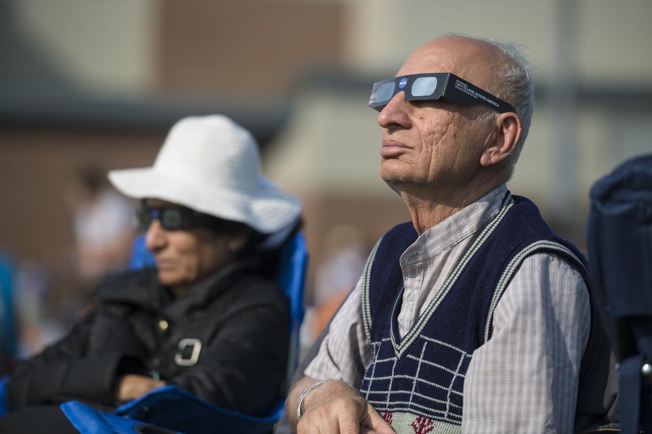 People are seen as they watch a total solar eclipse through protective glasses in Madras, Oregon on Monday, Aug. 21, 2017. A total solar eclipse swept across a narrow portion of the contiguous United States from Lincoln Beach, Oregon to Charleston, South Carolina. A partial solar eclipse was visible across the entire North American continent along with parts of South America, Africa, and Europe.  Photo Credit: (NASA/Aubrey Gemignani)