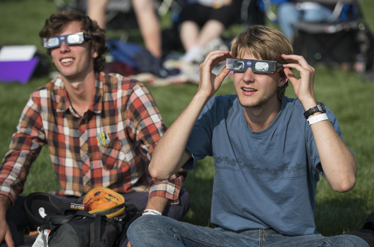 People are seen as they watch a total solar eclipse through protective glasses in Madras, Oregon on Monday, Aug. 21, 2017. A total solar eclipse swept across a narrow portion of the contiguous United States from Lincoln Beach, Oregon to Charleston, South Carolina. A partial solar eclipse was visible across the entire North American continent along with parts of South America, Africa, and Europe.  Photo Credit: (NASA/Aubrey Gemignani)