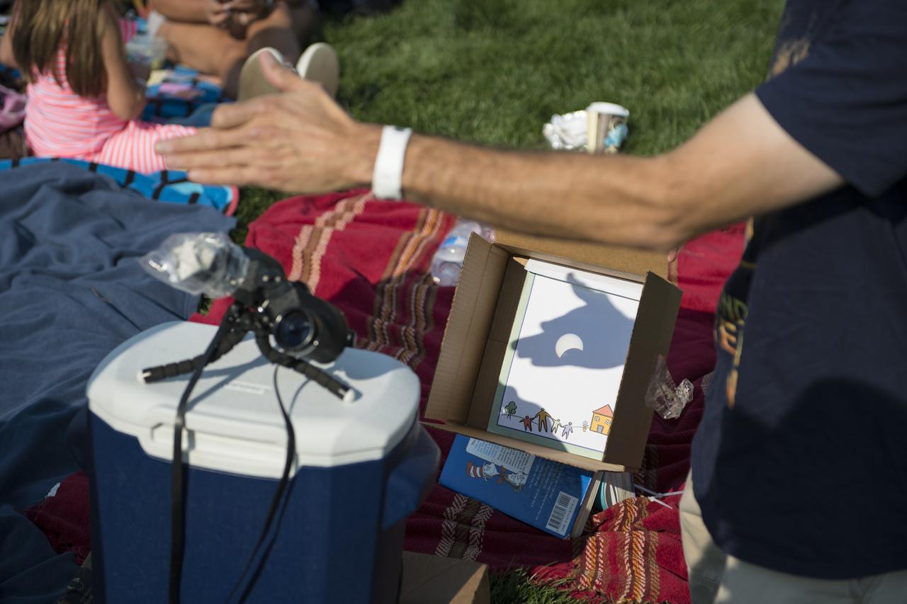 Dave Punaro reflects the shadow of the partial eclipse into a box during the total solar eclipse in Madras, Oregon on Monday, Aug. 21, 2017. A total solar eclipse swept across a narrow portion of the contiguous United States from Lincoln Beach, Oregon to Charleston, South Carolina. A partial solar eclipse was visible across the entire North American continent along with parts of South America, Africa, and Europe.  Photo Credit: (NASA/Aubrey Gemignani)