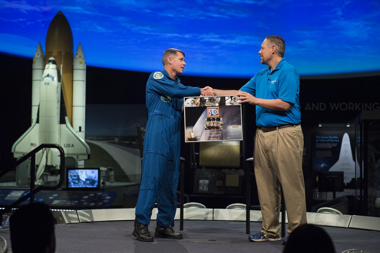 NASA astronaut Shane Kimbrough presents Marty Kelsey, STEM in 30 host, Smithsonian National Air and Space Museum (NASM), a montage with photos and a patch from Expedition 50, Tuesday, September 12, 2017 at Smithsonian's National Air and Space Museum in Washington. During Expedition 50, Kimbrough completed four spacewalks for a total of 39 hours outside the ISS, and concluded his 173-day mission when he landed in a remote area near the town of Zhezkazgan, Kazakhstan in April 2017. Photo Credit: (NASA/Aubrey Gemignani)