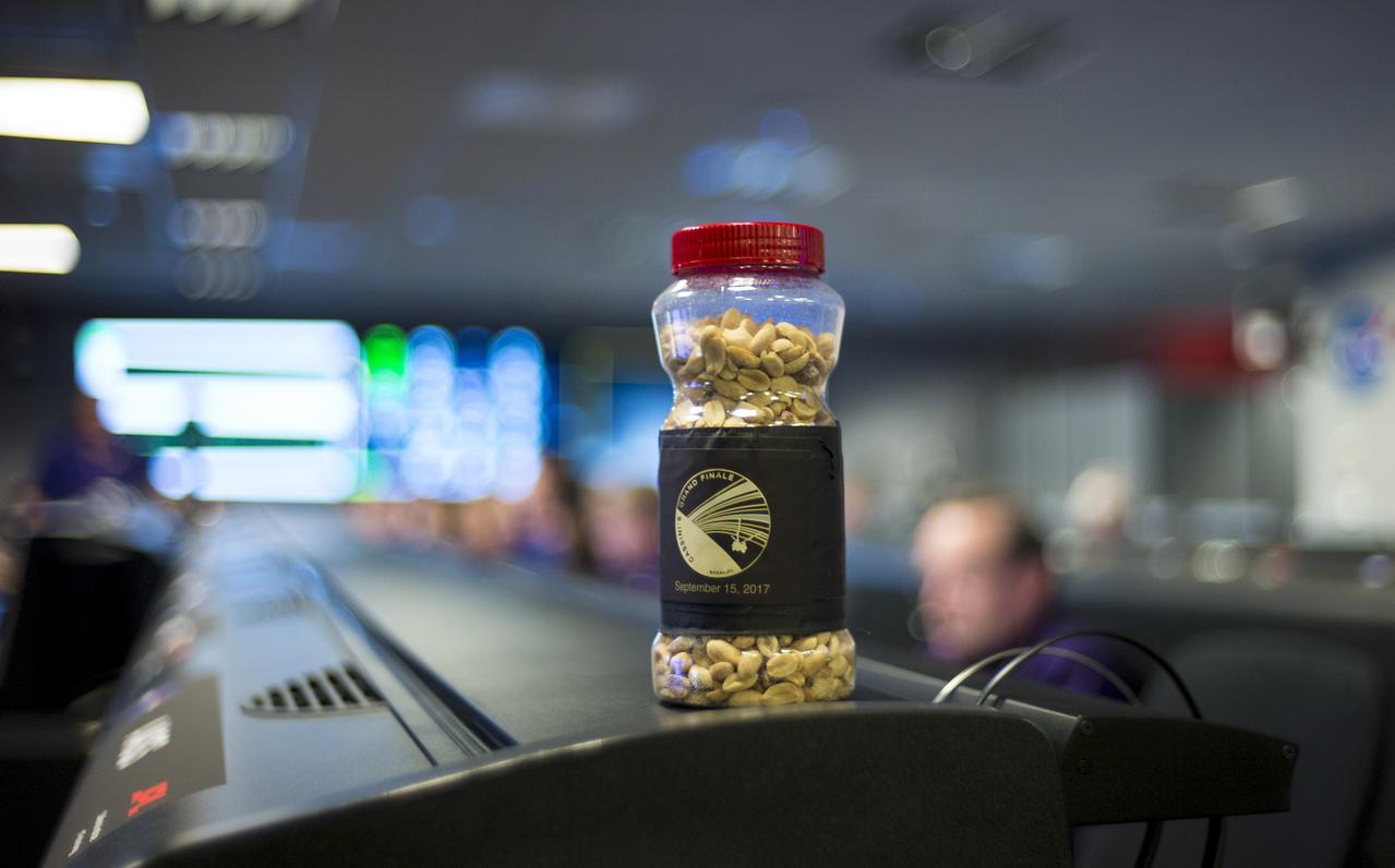 A jar of peanuts is seen sitting on a console in mission control of the Space Flight Operations Center as the Cassini mission team await the final downlink of the spacecraft's data recorder, Thursday, Sept. 14, 2017 at NASA's Jet Propulsion Laboratory in Pasadena, California. Since its arrival in 2004, the Cassini-Huygens mission has been a discovery machine, revolutionizing our knowledge of the Saturn system and captivating us with data and images never before obtained with such detail and clarity. On Sept. 15, 2017, operators will deliberately plunge the spacecraft into Saturn, as Cassini gathered science until the end. The “plunge” ensures Saturn’s moons will remain pristine for future exploration. During Cassini’s final days, mission team members from all around the world gathered at NASA’s Jet Propulsion Laboratory, Pasadena, California, to celebrate the achievements of this historic mission. Photo Credit: (NASA/Joel Kowsky)