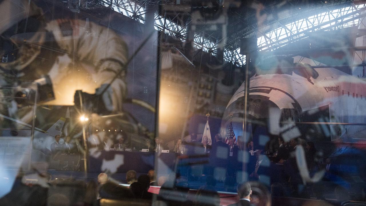 Members of the National Space Council are seen reflected in display case at the Smithsonian National Air and Space Museum's Steven F. Udvar-Hazy Center, during the council's first meeting, Thursday, Oct. 5, 2017 in Chantilly, Va. The National Space Council, chaired by Vice President Mike Pence heard testimony from representatives from civil space, commercial space, and national security space industry representatives.  Photo Credit: (NASA/Joel Kowsky)