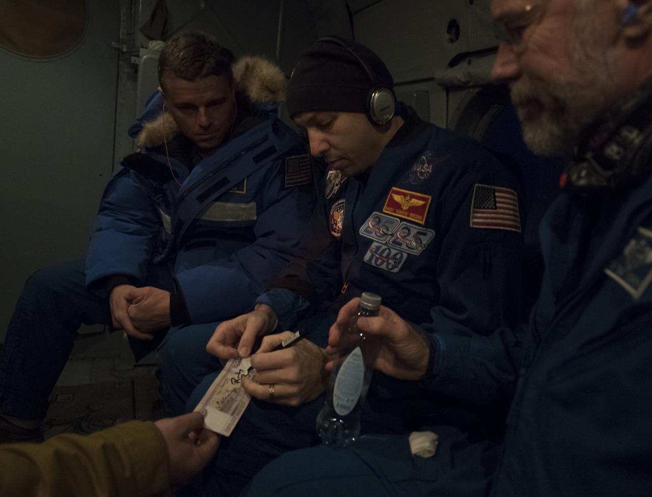 NASA astronaut Randy Bresnik, center, gives an autograph while onboard a helicopter shortly after he, ESA (European Space Agency) astronaut Paolo Nespoli, and Roscosmos cosmonaut Sergey Ryazanskiy landed in their Soyuz MS-05 spacecraft in a remote area near the town of Zhezkazgan, Kazakhstan on Thursday, Dec. 14, 2017. Looking on is NASA astronaut Reid Wiseman, left, and NASA Flight Surgeon Rick Scheuring. Bresnik, Nespoli and Ryazanskiy are returning after 139 days in space where they served as members of the Expedition 52 and 53 crews onboard the International Space Station. Photo Credit: (NASA/Bill Ingalls)