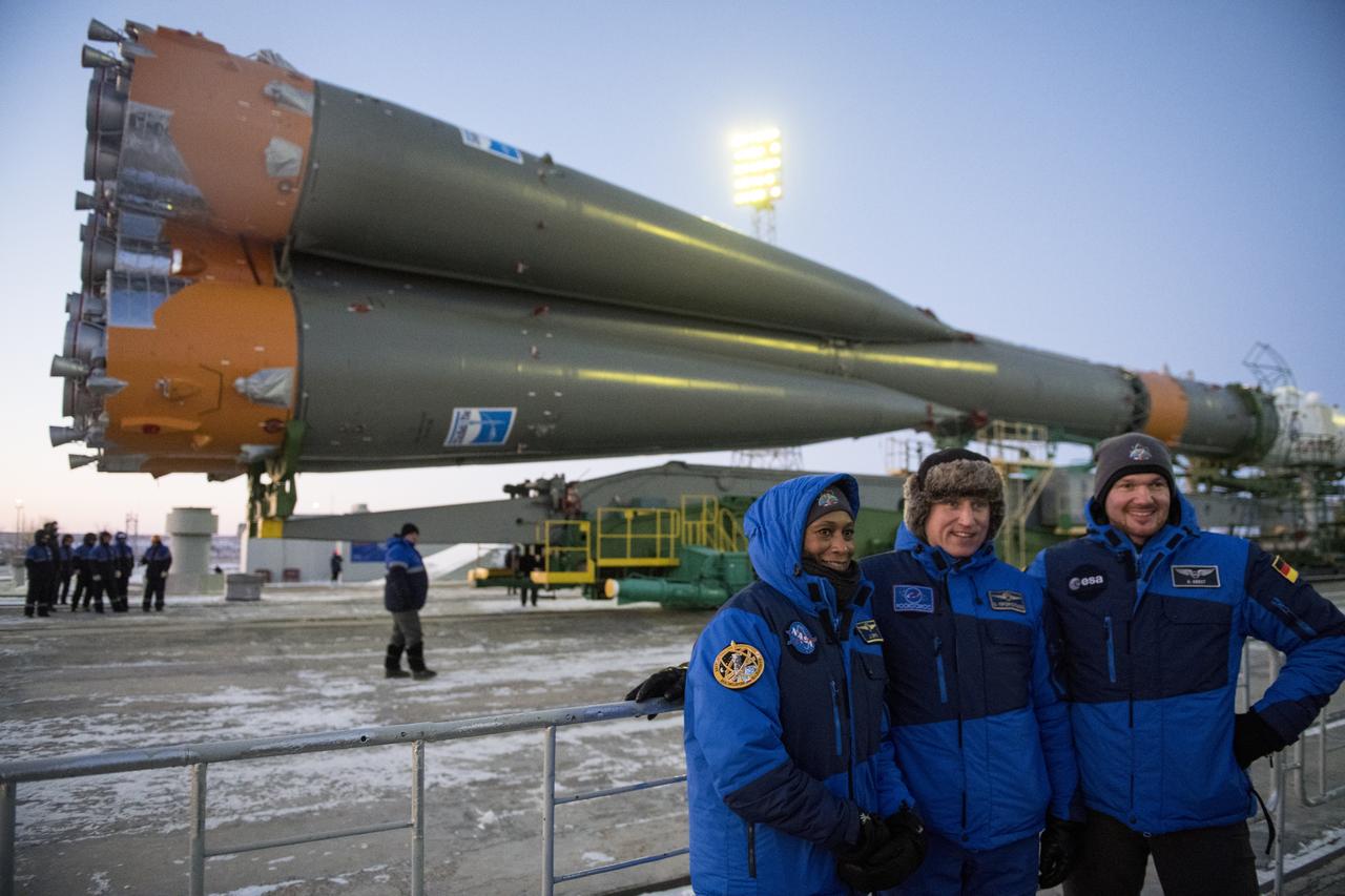 Expedition 54 backup crew members Jeanette Epps of NASA, left, Sergey Prokopev of Roscosmos, center, and Alex Gerst of ESA (European Space Agency), right, pose for a picture as the Soyuz rocket is rolled out to the pad, Friday, Dec. 15, 2017 at the Baikonur Cosmodrome in Kazakhstan. Expedition 54 Soyuz Commander Anton Shkaplerov of Roscosmos, flight engineer Scott Tingle of NASA, and flight engineer Norishige Kanai of the Japan Aerospace Exploration Agency (JAXA) are scheduled to launch at 2:21 a.m. Eastern Time (1:21 p.m. Baikonur time) on Dec. 17 and will spend the next five months living and working aboard the International Space Station.  Photo Credit: (NASA/Joel Kowsky)