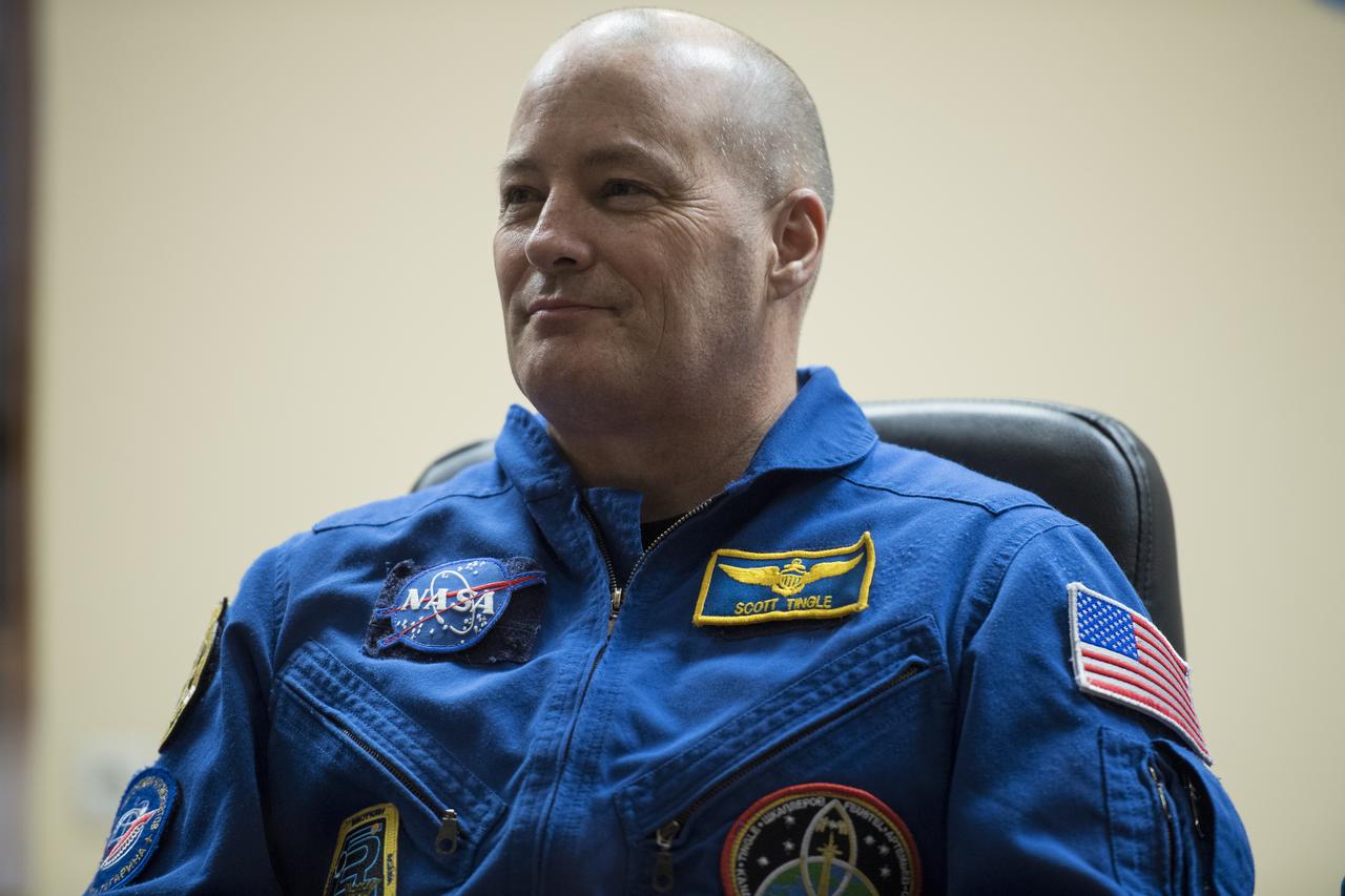 Expedition 54 flight engineer Scott Tingle is seen in quarantine, behind glass, during a press conference, Saturday, Dec. 16, 2017 at the Cosmonaut Hotel in Baikonur, Kazakhstan. Tingle, Soyuz Commander Anton Shkaplerov of Roscosmos, and flight engineer Norishige Kanai of the Japan Aerospace Exploration Agency (JAXA) are scheduled to launch to the International Space Station aboard the Soyuz spacecraft from the Baikonur Cosmodrome on December 17.  Photo Credit: (NASA/Joel Kowsky)