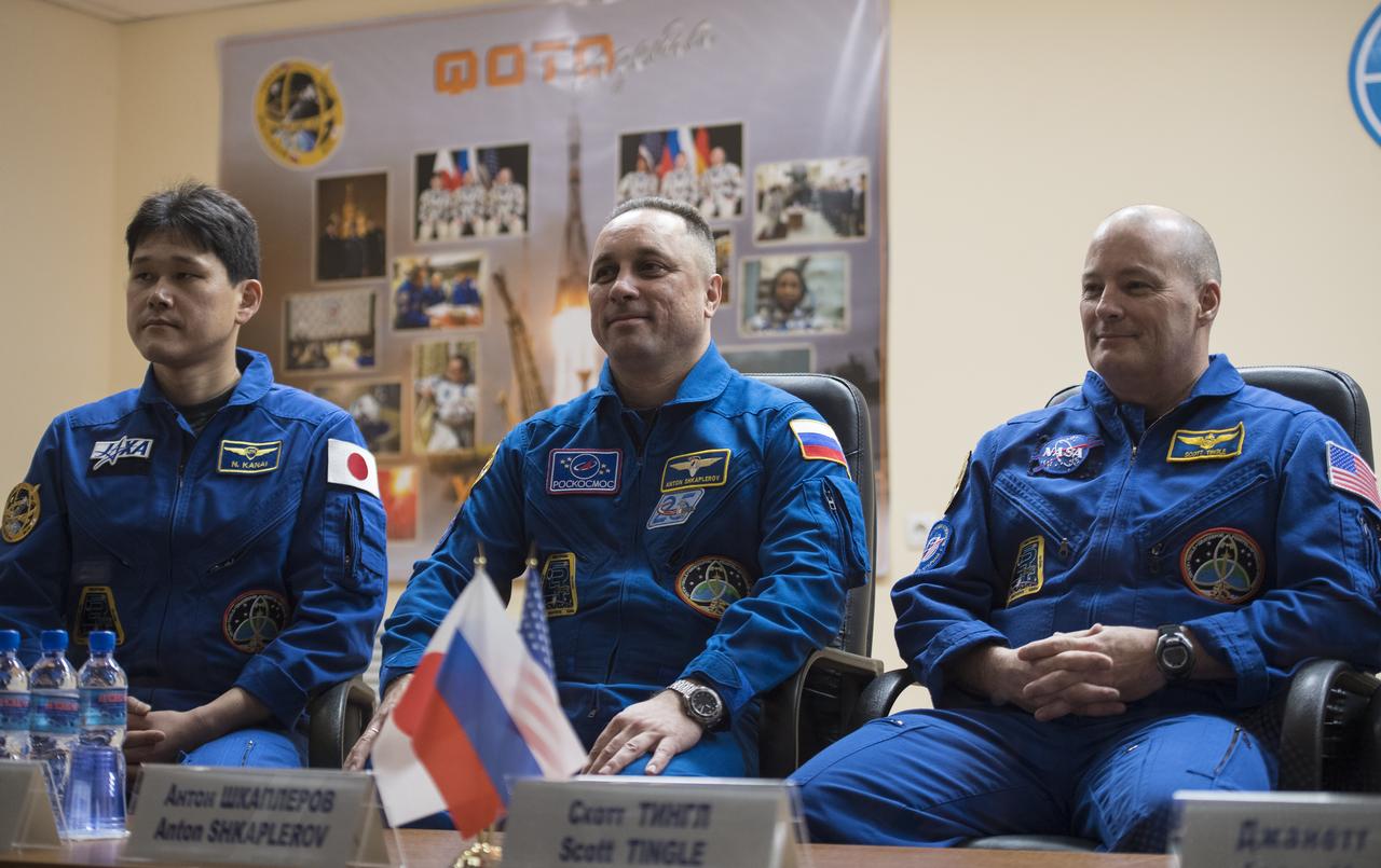 Expedition 54 prime crew members flight engineer Norishige Kanai of the Japan Aerospace Exploration Agency (JAXA), left, Soyuz Commander Anton Shkaplerov of Roscosmos, center, and flight engineer Scott Tingle of NASA, left, are seen in quarantine, behind glass, during a press conference, Saturday, Dec. 16, 2017 at the Cosmonaut Hotel in Baikonur, Kazakhstan. Kanai, Shkaplerov, and Tingle are scheduled to launch to the International Space Station aboard the Soyuz spacecraft from the Baikonur Cosmodrome on December 17.  Photo Credit: (NASA/Joel Kowsky)