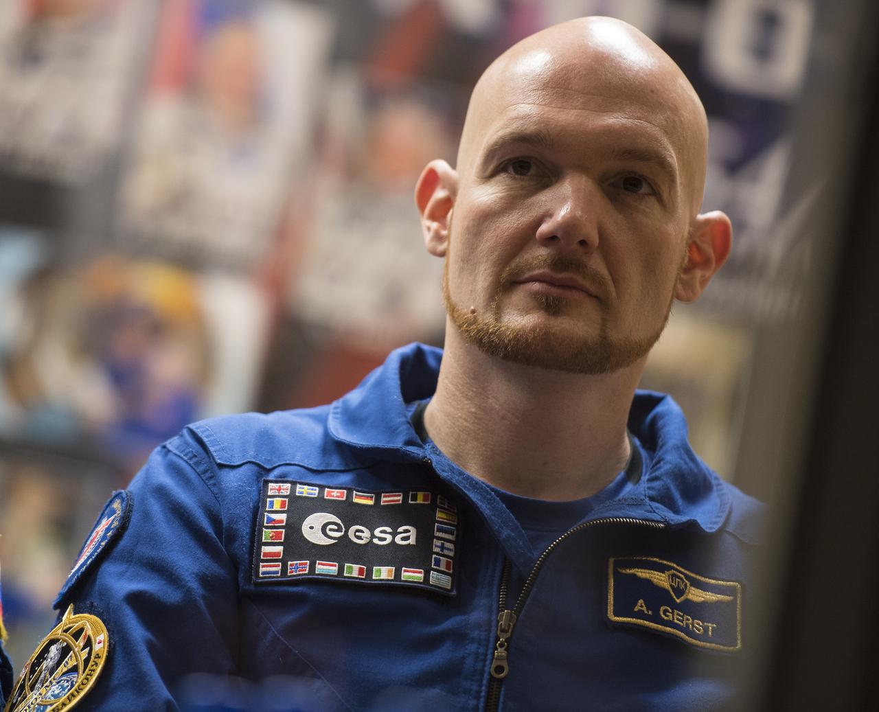 Expedition 54 backup crew member Alex Gerst of ESA (European Space Agency) is seen in quarantine, behind glass, during a press conference, Saturday, Dec. 16, 2017 at the Cosmonaut Hotel in Baikonur, Kazakhstan. Expedition 54 Soyuz Commander Anton Shkaplerov of Roscosmos, flight engineer Scott Tingle of NASA, and flight engineer Norishige Kanai of the Japan Aerospace Exploration Agency (JAXA) are scheduled to launch to the International Space Station aboard the Soyuz spacecraft from the Baikonur Cosmodrome on December 17.  Photo Credit: (NASA/Joel Kowsky)