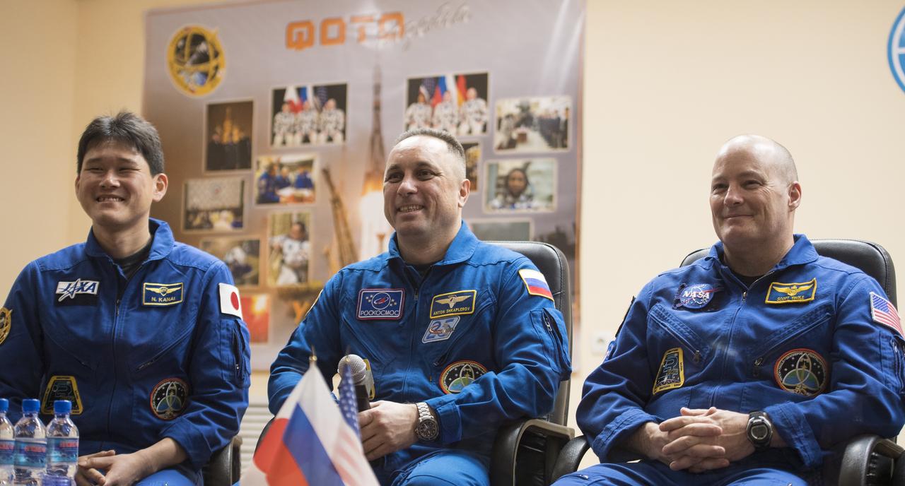 Expedition 54 prime crew members flight engineer Norishige Kanai of the Japan Aerospace Exploration Agency (JAXA), left, Soyuz Commander Anton Shkaplerov of Roscosmos, center, and flight engineer Scott Tingle of NASA during a press conference, Saturday, Dec. 16, 2017 at the Cosmonaut Hotel in Baikonur, Kazakhstan. Kanai, Shkaplerov, and Tingle are scheduled to launch to the International Space Station aboard the Soyuz spacecraft from the Baikonur Cosmodrome on December 17.  Photo Credit: (NASA/Joel Kowsky)