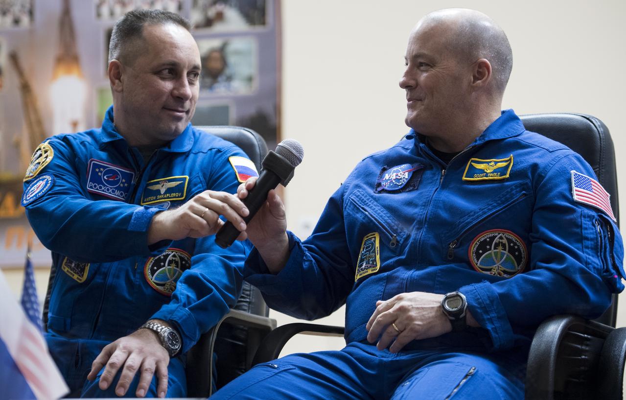 Expedition 54 Soyuz Commander Anton Shkaplerov of Roscosmos, left, passes a microphone to flight engineer Scott Tingle of NASA, right, while answering a question during a press conference, Saturday, Dec. 16, 2017 at the Cosmonaut Hotel in Baikonur, Kazakhstan. Expedition 54 Soyuz Commander Anton Shkaplerov of Roscosmos, flight engineer Scott Tingle of NASA, and flight engineer Norishige Kanai of the Japan Aerospace Exploration Agency (JAXA) are scheduled to launch to the International Space Station aboard the Soyuz spacecraft from the Baikonur Cosmodrome on December 17.  Photo Credit: (NASA/Joel Kowsky)