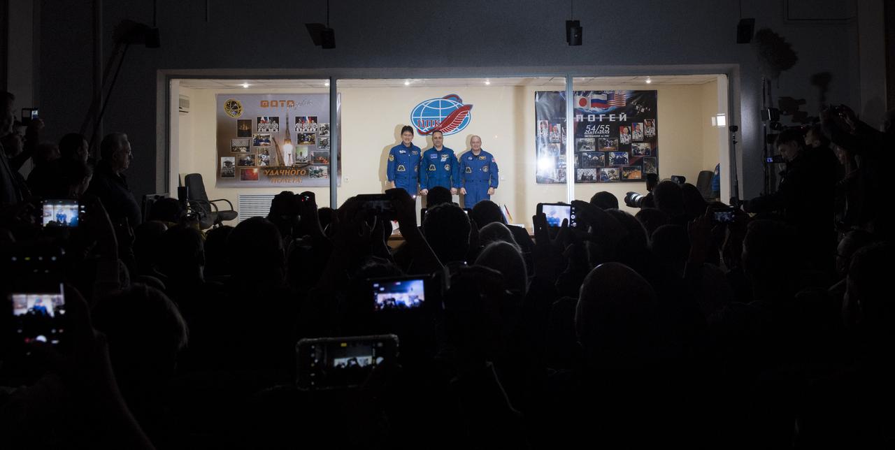 Expedition 54 prime crew members flight engineer Norishige Kanai of the Japan Aerospace Exploration Agency (JAXA), right, Soyuz Commander Anton Shkaplerov of Roscosmos, center, and flight engineer Scott Tingle of NASA, right, pose for a picture at the conclusion of a press conference, Saturday, Dec. 16, 2017 at the Cosmonaut Hotel in Baikonur, Kazakhstan. Expedition 54 Soyuz Commander Anton Shkaplerov of Roscosmos, flight engineer Scott Tingle of NASA, and flight engineer Norishige Kanai of Japan Aerospace Exploration Agency (JAXA) are scheduled to launch to the International Space Station aboard the Soyuz spacecraft from the Baikonur Cosmodrome on December 17.  Photo Credit: (NASA/Joel Kowsky)