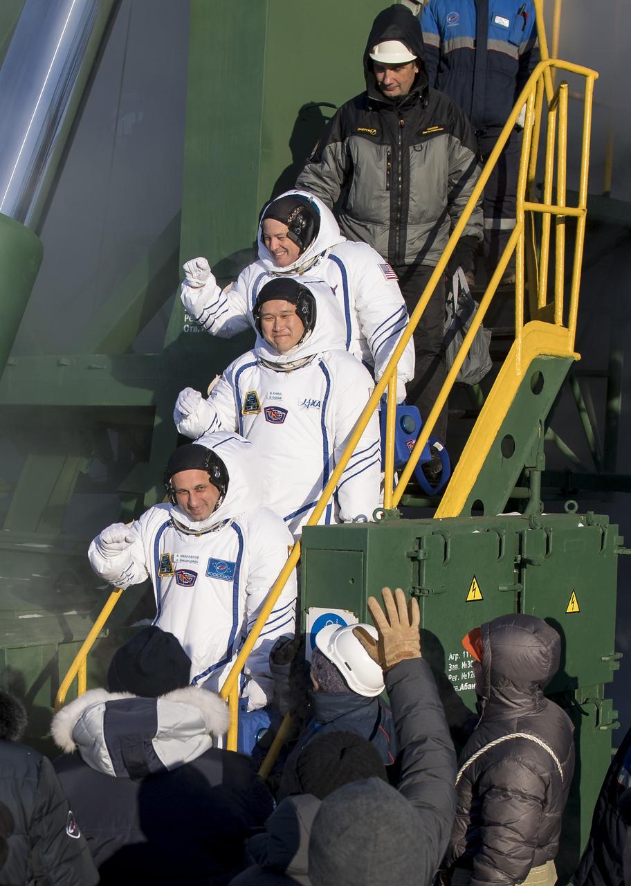 Expedition 54 flight engineer Scott Tingle of NASA, top, flight engineer Norishige Kanai of Japan Aerospace Exploration Agency (JAXA), middle, and Soyuz Commander Anton Shkaplerov of Roscosmos, bottom, wave farewell prior to boarding the Soyuz MS-07 rocket for launch, Sunday, Dec. 17, 2017 at the Baikonur Cosmodrome in Kazakhstan. Tingle, Norishige Kanai, and Shkaplerov will spend the next five months living and working aboard the International Space Station.  Photo Credit: (NASA/Joel Kowsky)